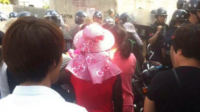 Fully-armed police officers block Christians protesting the demolition.