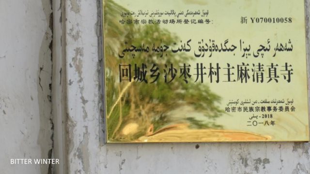 This Jummah mosque is in Shazaojing village of the Huicheng township in Kumul. The crescent moon and star symbols on top of the mosque have all been removed, and tight wire netting has been attached to the surrounding walls. The notice at the entrance reads: “Party members, state officials, and minors not allowed in religious establishments.”