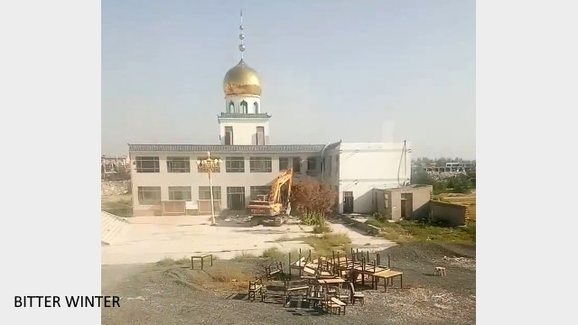 Excavator demolishing part of the mosque building with obvious Islamic characteristics