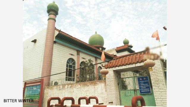 The mosque in Liugong village’s No.7 Production Team has been shut down, and the perimeter wall has been covered with barbed wire. Two Chinese flags have been erected, one on each side of the entrance.
