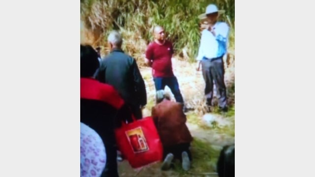 An elderly person in Wanzhai village gets on his knees and begs the town mayor. (Provided by an inside source)