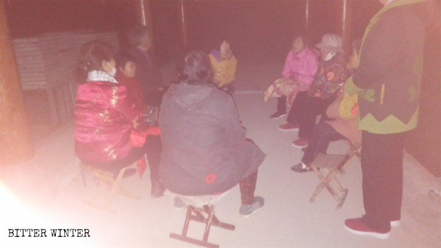 Elderly Christians are gathering in a gazebo outside the village while it is dark outside.
