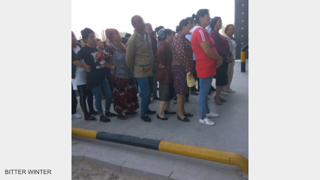 The detainees’ family members who are attending the public trial meeting line up outside the re-education camp, waiting to be summoned