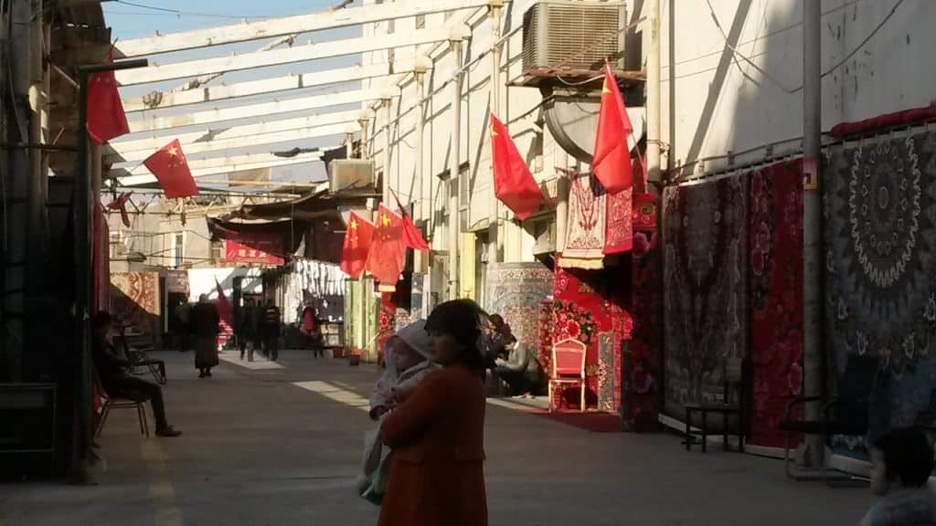 Red flags on display in a market in the city of Turpan. Summer 2018.