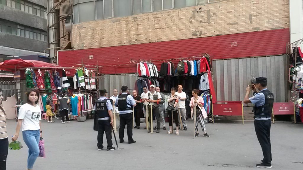 Urumqi back street traders being photographed by the community police following a 'weapons' drill. August 2018.
