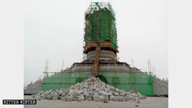 Three-faced Guanyin statue being demolished, and fragments of the structure litter the ground.
