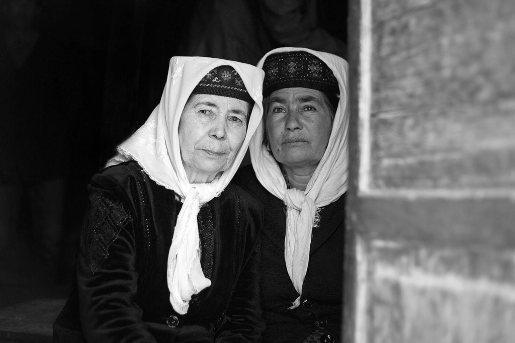 Two women of the Tajik minority snuggle together.