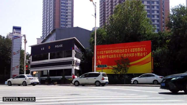 Police station, surveillance cameras, and large propaganda poster in Urumqi.