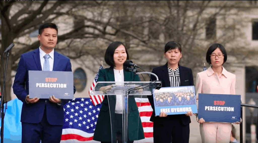 Sister Jiao of The Church of Almighty God speaks, while other members of her Church hold signs of solidarity with the Uyghurs