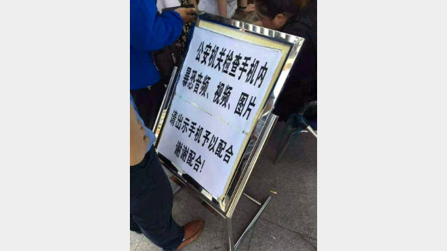 A warning sign at a border post in Xinjiang, informing that everyone crossing the border will have their mobile phones checked. (by Radio Free Asia reporter Qiao Long)