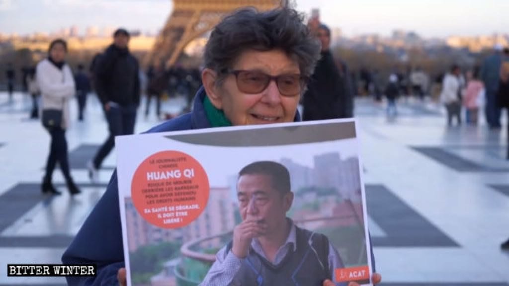 A woman from ACAT is holding a photo of Huang Qi in her hands.