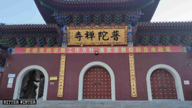 An utterly ironic CCP propaganda slogan, reading “Implement the policy of freedom of religious belief,” hangs in front of Putuo Temple.