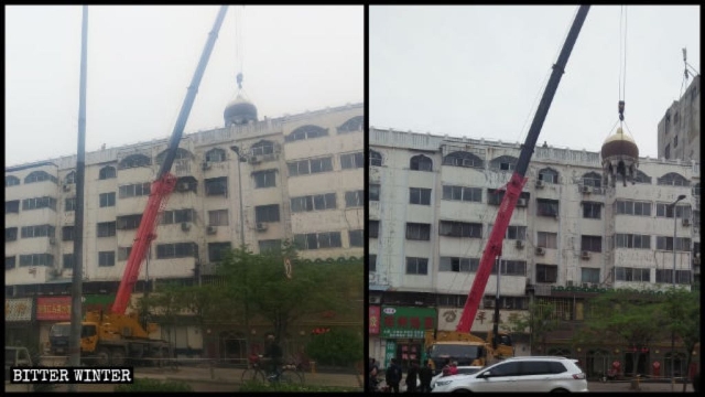 A crane dismantles a round Islamic structure at the top of a building