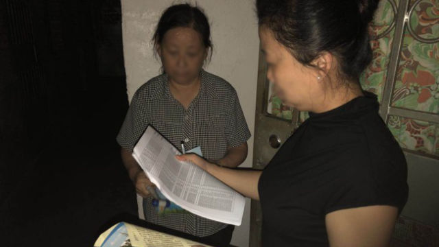 A government official visits a believer’s home and registers her information.