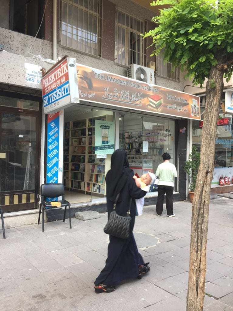 A Uyghur “widow” passing a Uyghur bookstore in Istanbul.