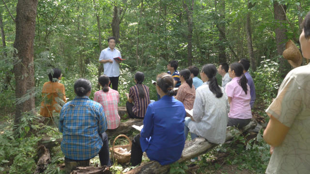 Believers of a house church are holding a meeting in the woods.