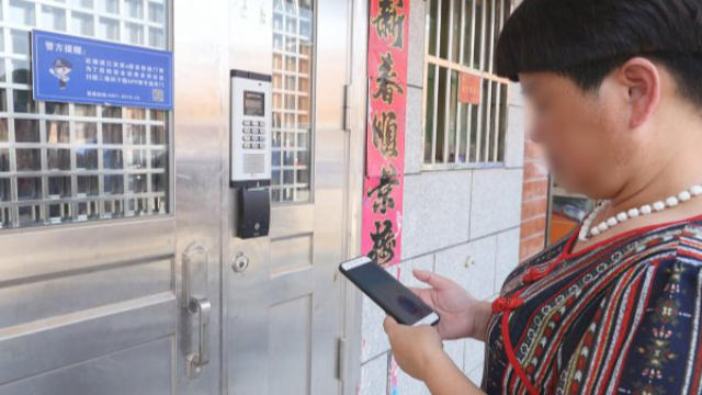 A tenant is using the mobile app to open the smart door lock.