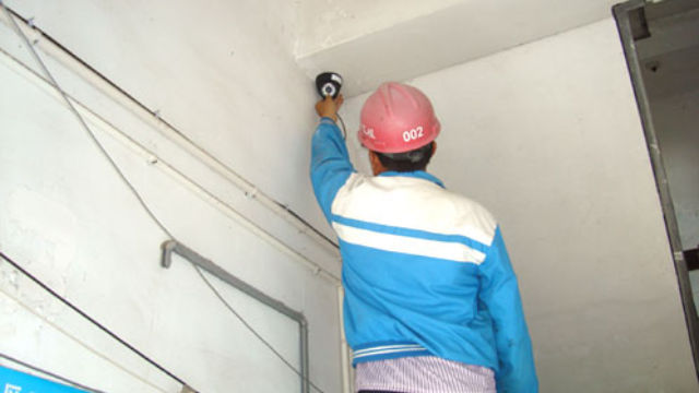 A worker is installing a surveillance camera.