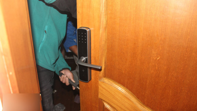 A worker is installing the smart lock at a rental property.