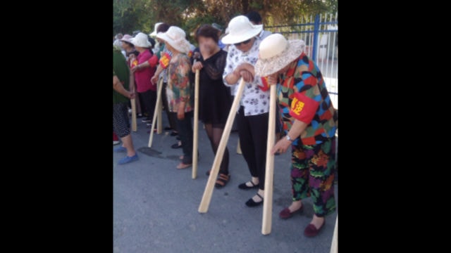People in a locality of Xinjiang are carrying wooden bats as they participate in “counter-terrorism drills.”