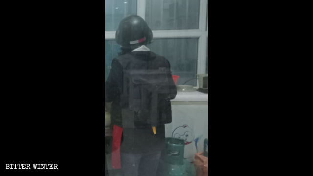 A cafe waitress wears a bulletproof vest and a helmet while at work.